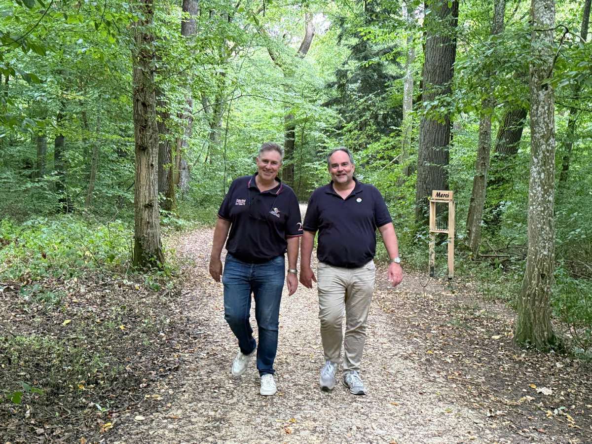 Filip and Olivier walking side by side along a forest path.
